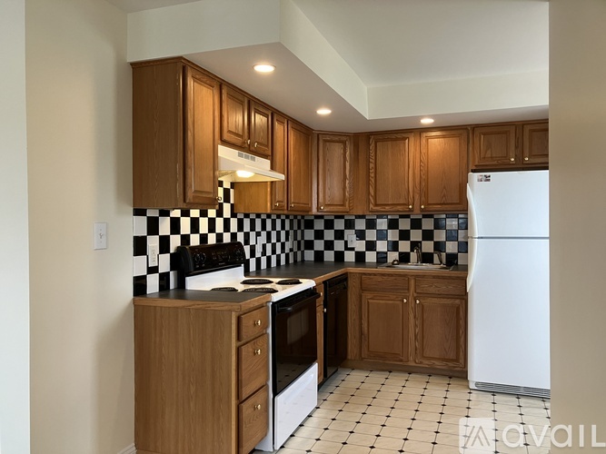 A kitchen with black and white tiles and wooden cabinets.