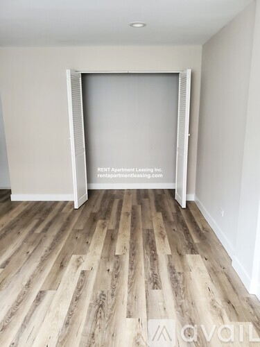 A room with wooden flooring and a white door with a sign that says "RENT Apartment Leasing Inc.".