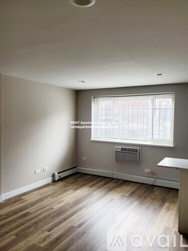 A room with a window and a wooden floor.