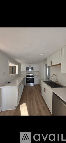 A kitchen with white cabinets and a wooden floor.