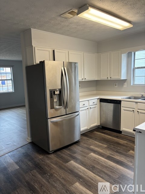 A kitchen with a stainless steel refrigerator and wooden flooring.