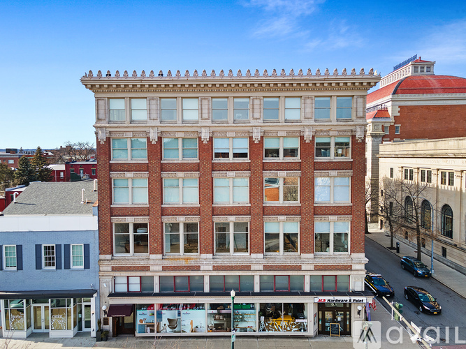 A street view of a city with a red brick building in the center.