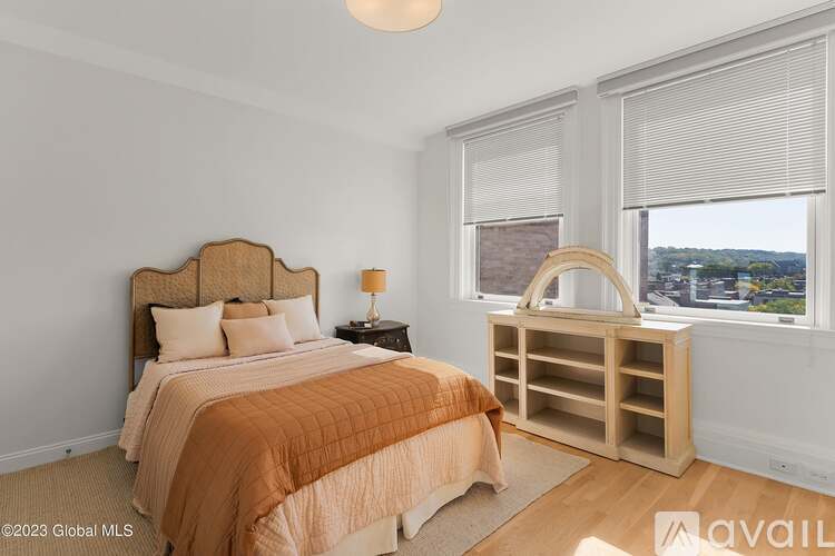 A bedroom with a bed, nightstand, and window with blinds.
