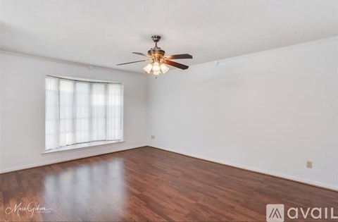 A room with a ceiling fan and a window with blinds.