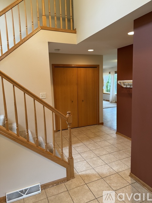 A wooden staircase with a glass balustrade leads to a landing with a brown door.