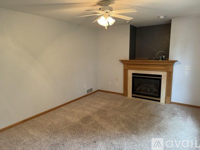 A living room with a fireplace and a ceiling fan.