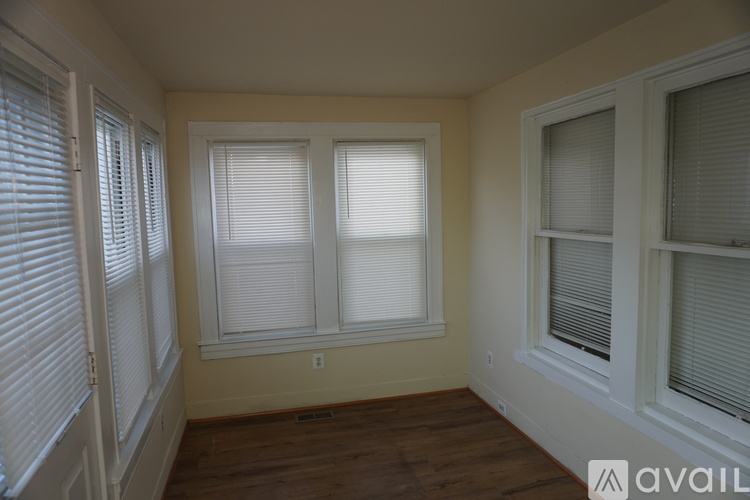 A room with wooden floors and three windows with blinds.
