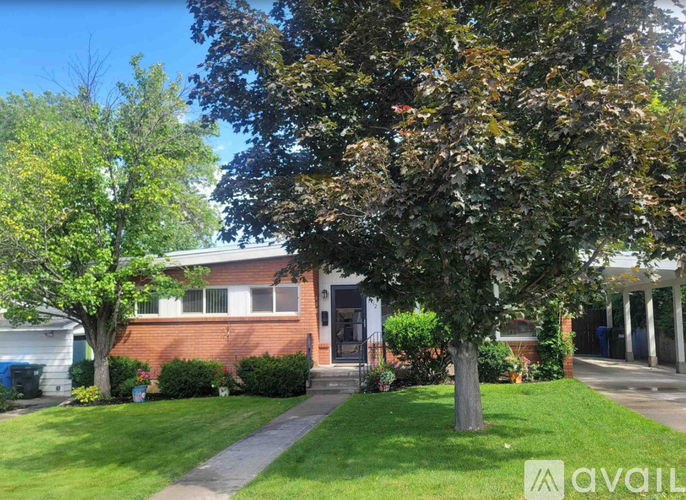 A house with a red brick exterior and a tree in front.