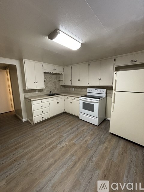 A kitchen with white cabinets and a wooden floor.