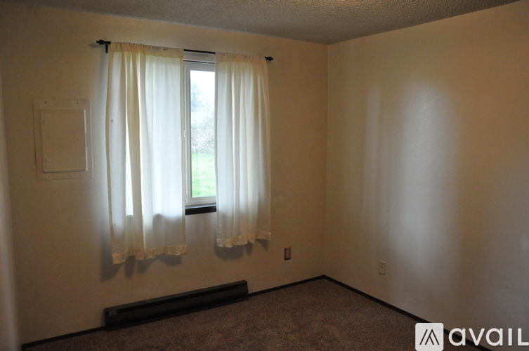 A room with a window covered by white curtains.