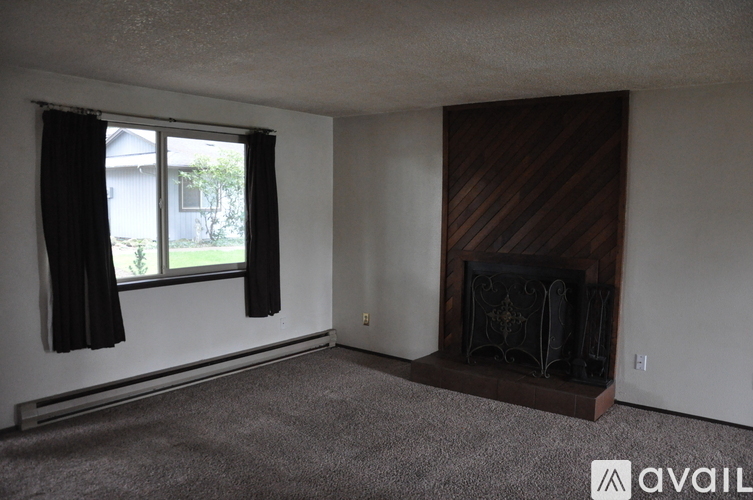 A living room with a fireplace and a window with curtains.