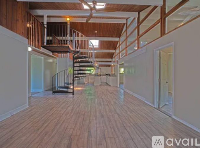 A spacious room with wooden floors and a staircase with a metal railing.
