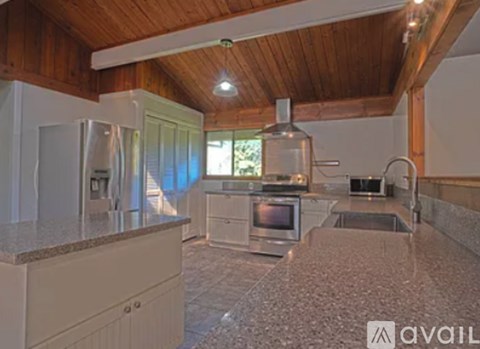 A kitchen with a refrigerator, microwave, oven, and sink.