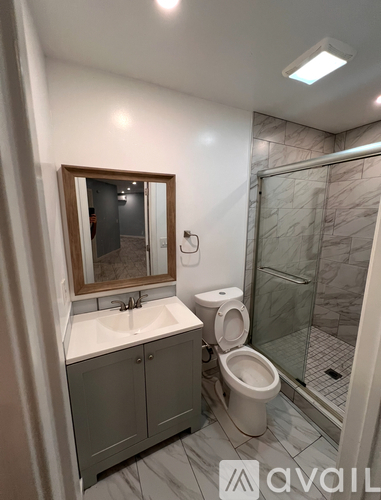 A bathroom with a toilet, sink, and mirror.