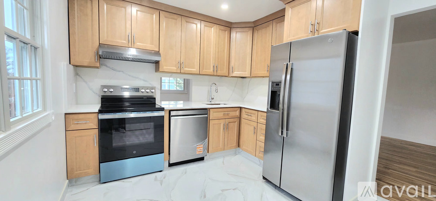 A kitchen with wooden cabinets and a stainless steel refrigerator.