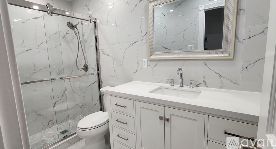 A white bathroom with a marble wall and a white toilet.