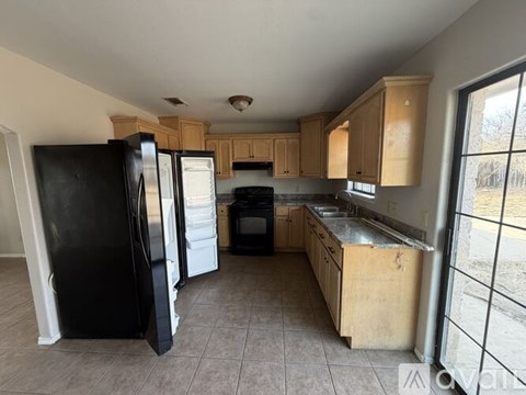 A kitchen with black and white appliances and wooden cabinets.