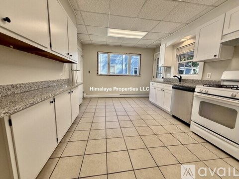 A kitchen with white cabinets and a granite countertop is available for rent.