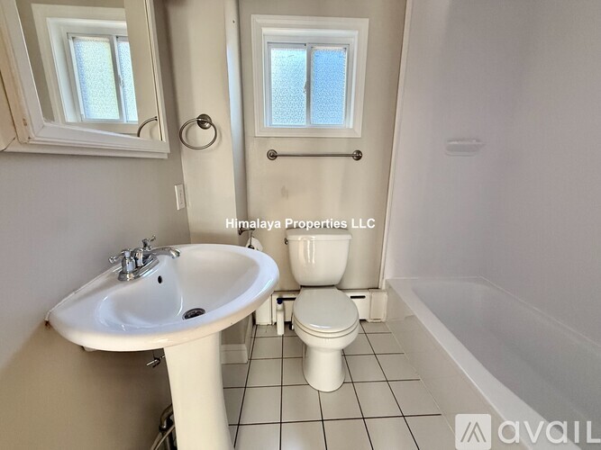 A white bathroom with a sink, toilet and window.