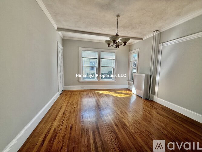 A spacious room with wooden floors and a ceiling fan, available for rent.