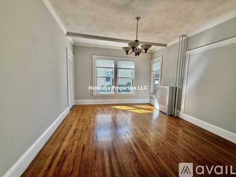 A spacious room with wooden floors and a ceiling fan, available for rent.