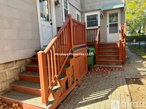 A wooden staircase with a railing is in front of a house.