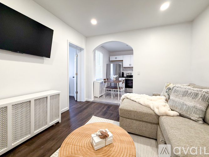 A living room with a couch, a coffee table, and a television mounted on the wall.