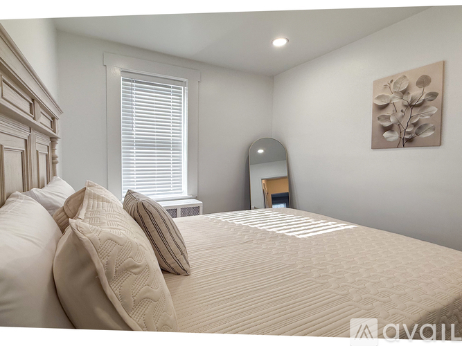 A bedroom with a large bed and a painting on the wall.