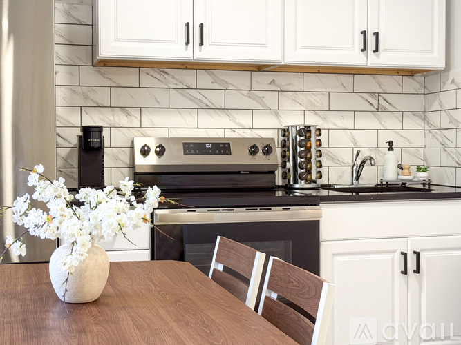 A kitchen with a stove top oven and a vase of flowers on the table.