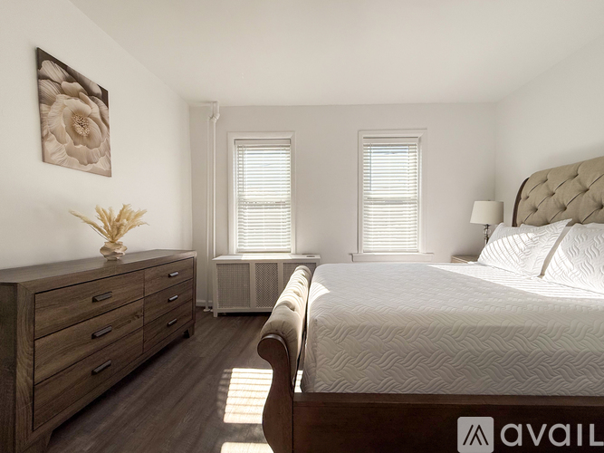 A bedroom with a large bed, wooden dresser, and a framed picture on the wall.