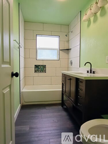 A bathroom with a green wall and a white tub.