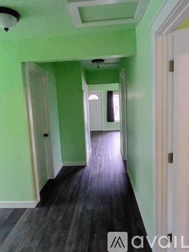 A hallway with green walls and a wooden floor.
