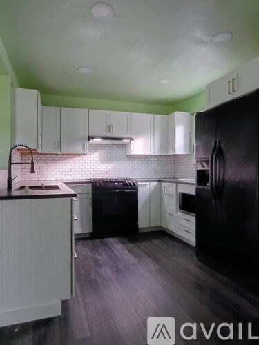 A kitchen with black appliances and white cabinets.