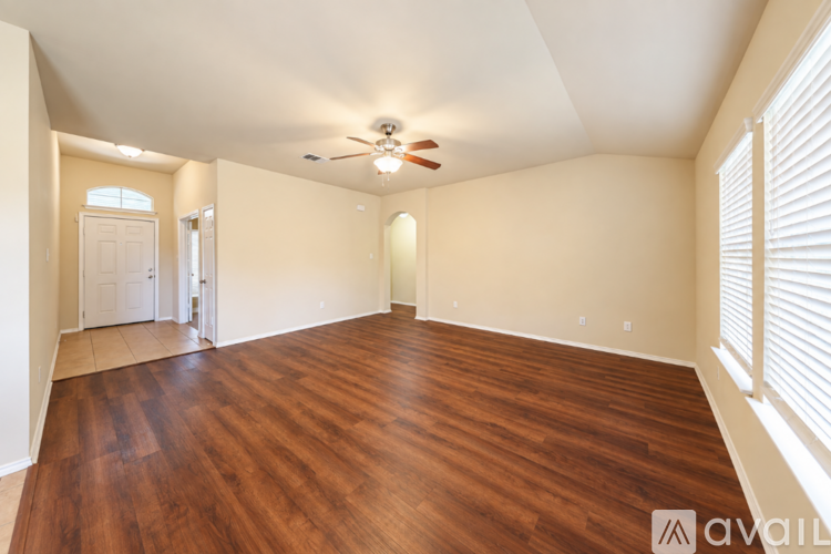 A spacious room with wooden flooring and a ceiling fan.