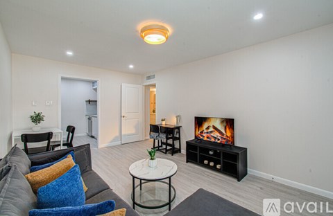 A living room with a grey couch, a white coffee table, and a television on a black stand.