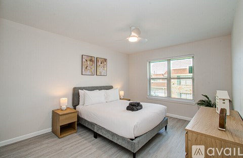 A bedroom with a bed, nightstand, and window.