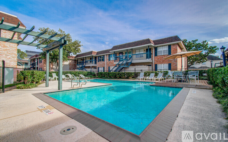 A pool area with a clear blue pool and a building in the background.