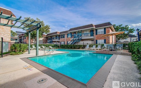 A pool area with a clear blue pool and a building in the background.