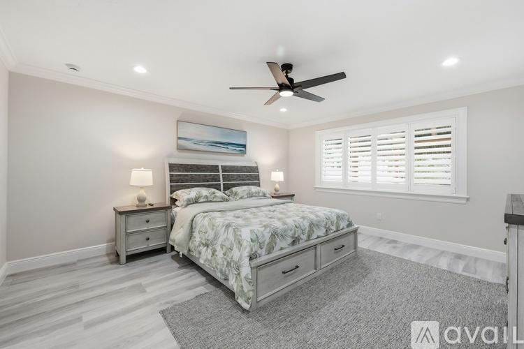 A bedroom with a bed, nightstands, and a ceiling fan.