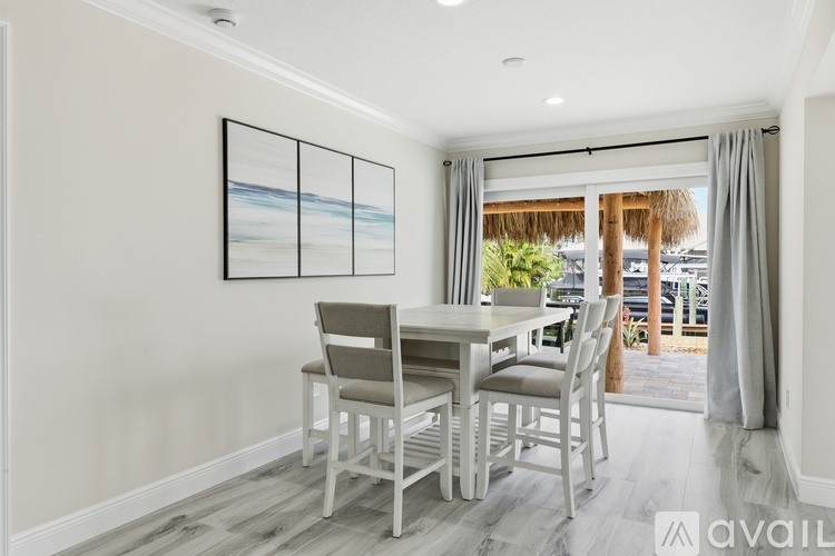 A dining room with a table and chairs and a painting on the wall.