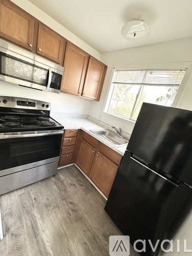 A kitchen with a black fridge and a black stove top.