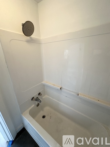 A white bathroom with a tub and shower head.