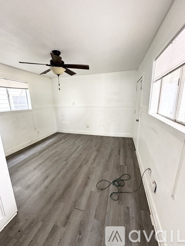 A room with a ceiling fan and wooden flooring.