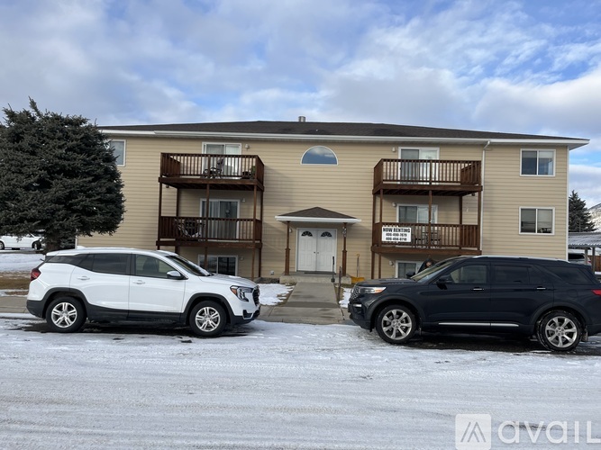 Two cars are parked in front of a two-story apartment building.