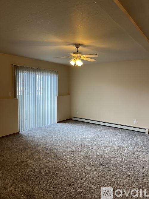 A room with a ceiling fan and carpeted floor.
