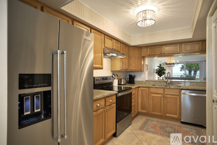 A kitchen with a stainless steel refrigerator and wooden cabinets.