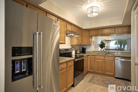 A kitchen with a stainless steel refrigerator and wooden cabinets.