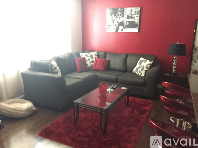 A living room with a grey couch, a red coffee table, and a red rug.