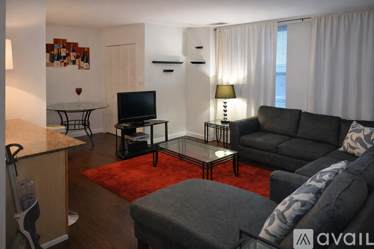 A living room with a grey couch, a glass table, and a television.