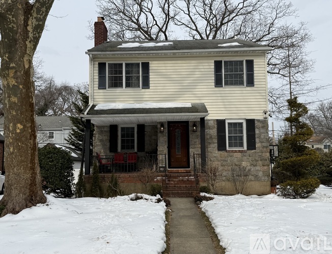 A house with a white siding and a brown door is surrounded by snow.
